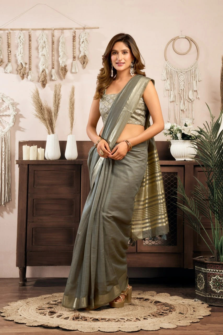 Woman in a gray saree standing in a room with decorative elements.